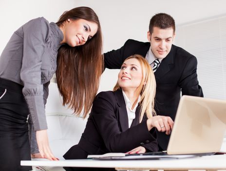 Happy Business woman showing her colleagues project at laptop in the office.