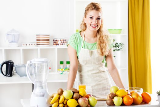 Beautiful young woman in a kitchen with fruits. Looking at camera.