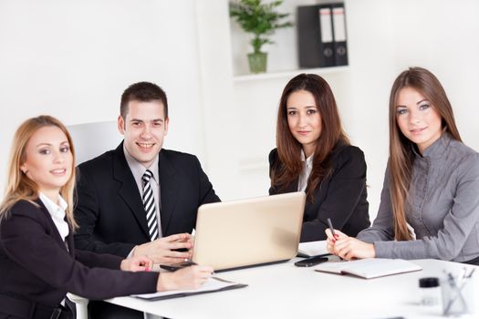 Four happy Business people in the office. Looking at camera.