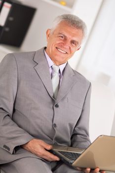 Happy Senior businessman working on laptop.