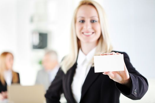 Beautiful young businesswoman holding Blank business card in the office. Looking at camera. Selective Focus, focus on card.