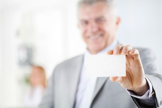 Happy senior businessman holding Blank business card in the office. Looking at camera. Selective Focus. Focus on business card.