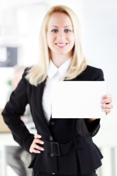 Beautiful young businesswoman holding Blank business card in the office. Looking at camera. Selective Focus. Focus on card.