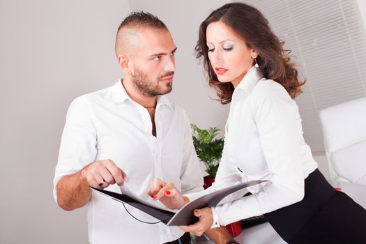 Business man and business woman looking in folder and talking about business project