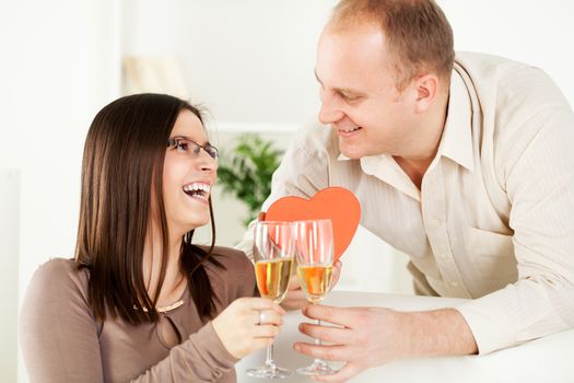 Happy Young couple in home interior enjoying in glass of champagne. The valentine's day.