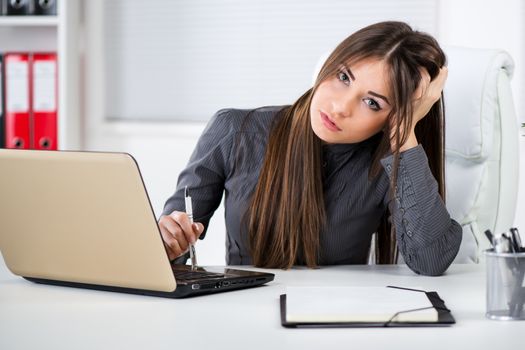 Worried Businesswoman in the office, sitting and thinking about problems. Looking at camera.