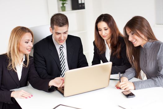 Four happy Business people looking project at laptop in the office.