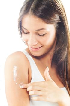 Beautiful young woman applying body lotion.