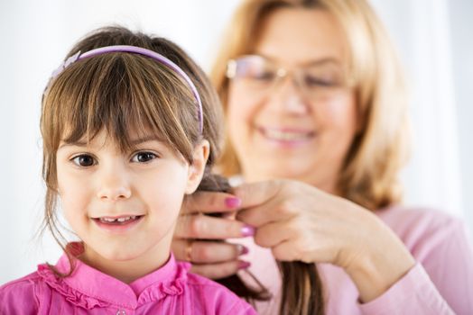 Beautiful Grandmother making Braid to cute granddaughter 