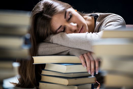 Tired student fell a sleep between many books, while learning. Selective focus.