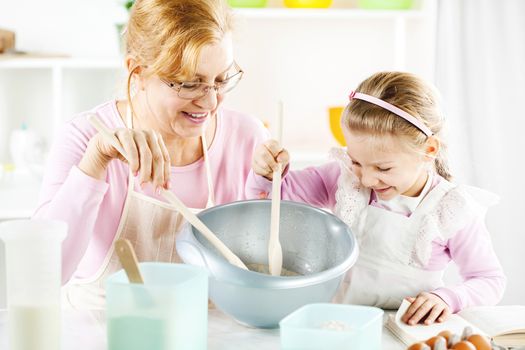 Beautiful happy grandmother learning her granddaughter Baking in a kitchen. 