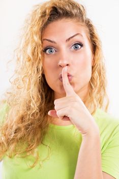 Portrait of beautiful young woman with Finger on Lips  gesturing for quiet or shushing. Close-up.