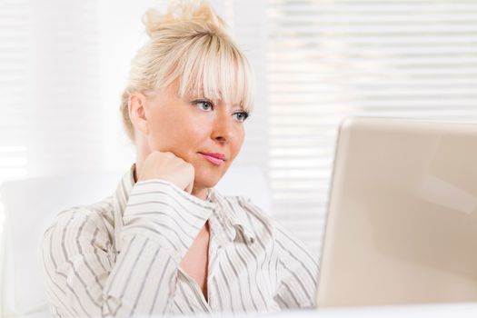 Beautiful mature Business woman sitting in the office and looking with laptop.