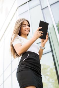 Happy Businesswoman standing on the street in front of Office Building and using a Tablet PC.