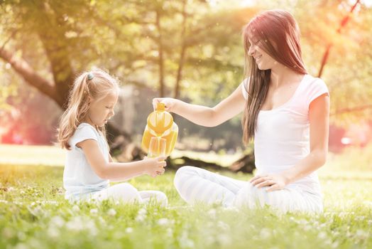 Beautiful Mother and daughter in the nature having little picnic.