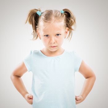 Cute angry little girl standing with hands on hips.
