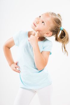 Cute little girl standing against a white background and thinking...