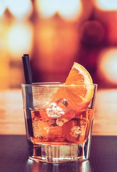 glass of spritz aperitif aperol cocktail with orange slices and ice cubes on bar table, vintage atmosphere background, lounge bar concept