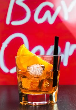 glass of spritz aperitif aperol cocktail with orange slices and ice cubes on bar table, disco atmosphere background, lounge bar concept