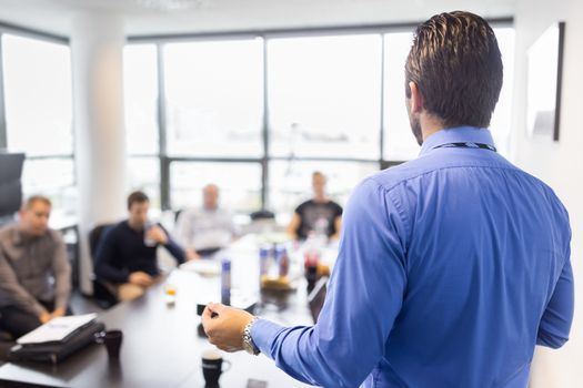 Business man making a presentation at office. Business executive delivering a presentation to his colleagues during meeting or in-house business training, explaining business plans to his employees. 