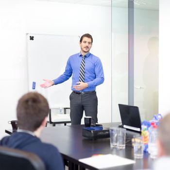 Business man making a presentation at office. Business executive delivering a presentation to his colleagues during meeting or in-house business training, explaining business plans to his employees.