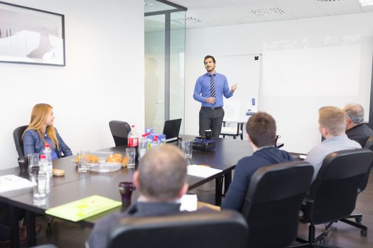 Business man making a presentation at office. Business executive delivering a presentation to his colleagues during meeting or in-house business training, explaining business plans to his employees.