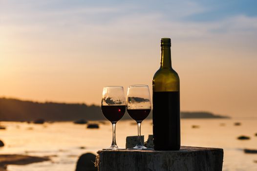 Red wine bottle and glasses on the shore in evening