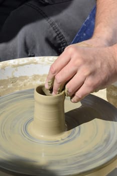 Potter at small wheel with pot                                                                                                                                                                                                                        