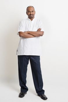 Full body casual mature Indian business people arms crossed standing on plain background.