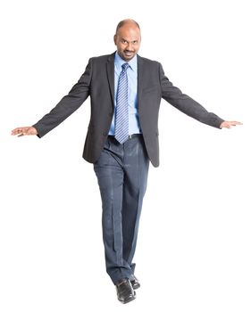 Full body Indian businessman walking balance , front view on plain background.