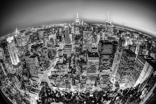 New York City. Manhattan downtown skyline with illuminated Empire State Building and skyscrapers at dusk seen from observation deck. Fish eye panoramic view. Black and white photo.