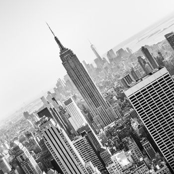 New York City. Manhattan downtown skyline with illuminated Empire State Building and skyscrapers at sunset. Vertical composition. Black and white image. Square composition.