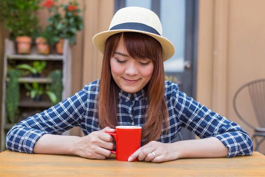 wear hat woman sitting in outdoor with warm drink relax