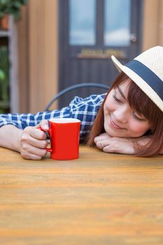 wear hat woman sitting in outdoor with warm drink relax