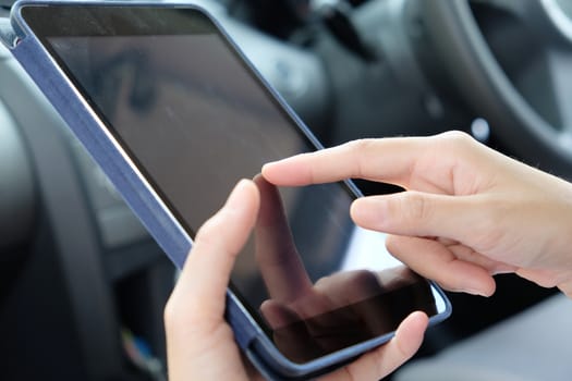 Woman Sitting in the Car and Using digital tablet.