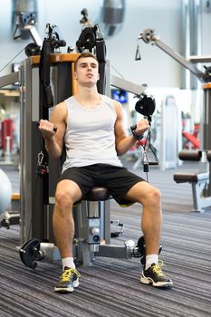 sport, fitness, equipment, lifestyle and people concept - man exercising on gym machine