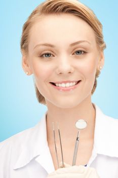 people, medicine, stomatology and healthcare concept - happy young female dentist with tools over blue background