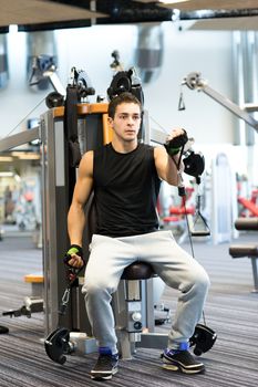 sport, fitness, equipment, lifestyle and people concept - man exercising on gym machine