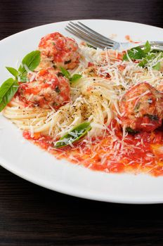 Pasta in tomato gravy with meatballs sprinkled Parmesan and basil