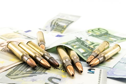 Composition with golden bullets and colorful banknotes.