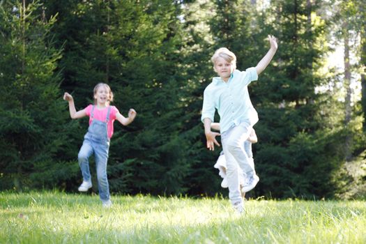 Group of young children running towards camera in park