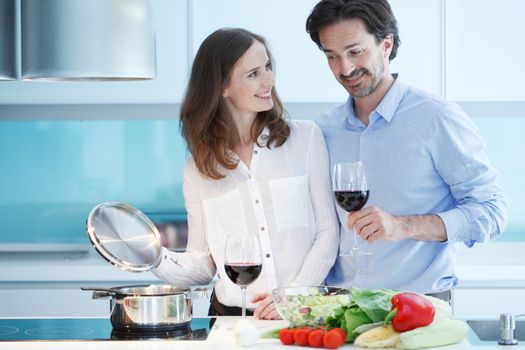 Portrait of a couple having a glass of red wine while cooking dinner