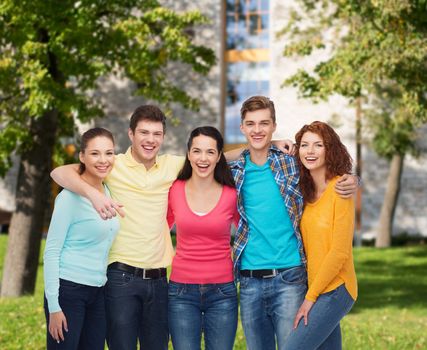 friendship, education, summer vacation and people concept - group of smiling teenagers standing and hugging over campus background