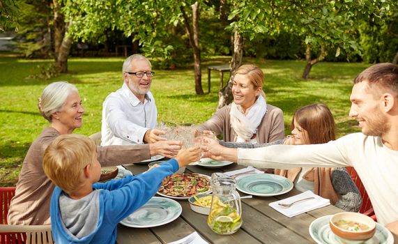 family, generation, home, holidays and people concept - happy family having dinner and clinking glasses in summer garden