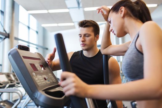 sport, fitness, lifestyle, technology and people concept - tired woman with trainer exercising on stepper in gym