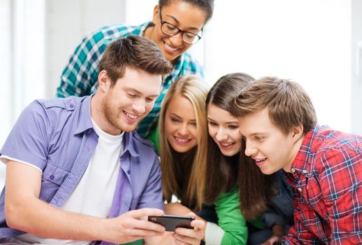 education and technology - group of students looking at smartphone at school