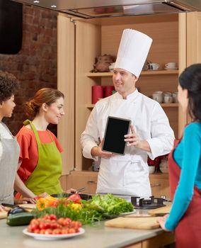 cooking class, culinary, food, technology and people concept - happy women with chef cook showing blank tablet pc screen in kitchen