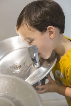 Mixed Race Boy Drinking From the Fresh Water Fountain.