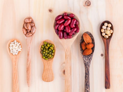 Assortment of beans and lentils in wooden spoon on wooden background. mung bean, groundnut, soybean, red kidney bean and almond.