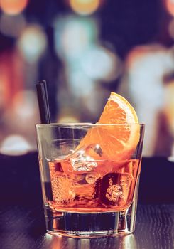 glass of spritz aperitif aperol cocktail with orange slices and ice cubes on bar table, vintage atmosphere background, lounge bar concept